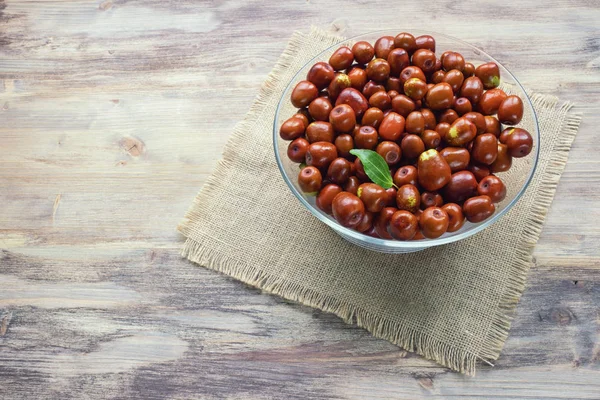 Jujube fruits  ( Ziziphus jujuba ) in glass bowl on rustic background. Free space for text