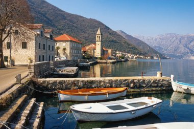 Dağlara karşı küçük bir Akdeniz köyü. Karadağ, Adriyatik Denizi. Güneşli kış gününde Kotor Körfezi ve Stoliv köyü manzarası