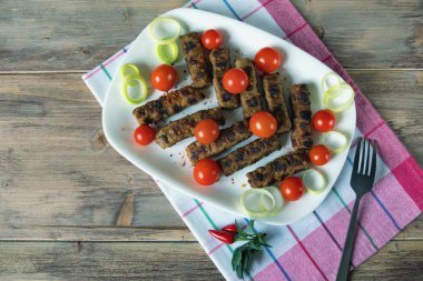 Balkan mutfağı. Cevapi - ızgara et - beyaz tabakta. Kırsal arkaplan, düz yatış, metin için boş alan 