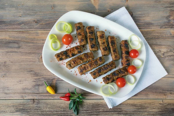 Kuchnia bałkańska. Cevapi - grillowane danie z mielonego mięsa. Rustykalne tło, płaski leżak, wolne miejsce na tekst — Zdjęcie stockowe