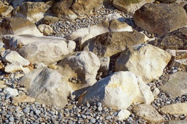 Güneşli bir günde beyaz ve koyu taşlar ve çakıl taşları, doğal arka plan.