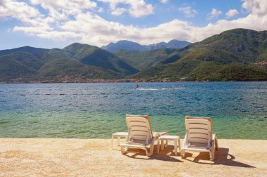 Yaz tatili. Sahilde iki şezlonglu güzel güneşli manzara. Karadağ, Adriyatik Denizi ve Tivat kenti yakınlarındaki Kotor Körfezi manzarası