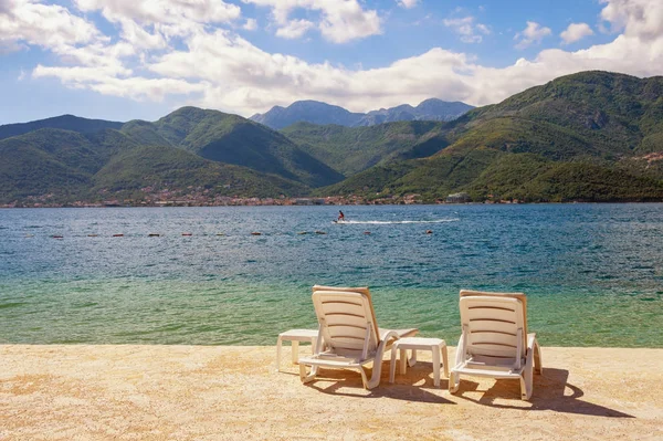 Vacaciones de verano. Hermoso paisaje soleado con dos chaise lounges en la playa. Montenegro, Mar Adriático, vista de la bahía de Kotor cerca de la ciudad de Tivat — Foto de Stock