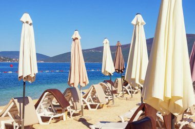 Yaz tatili kavramı. Kumsalda güneşli bir gün. Güneş şemsiyeli şezlonglar. Karadağ, Adriyatik Denizi, Kotor Körfezi