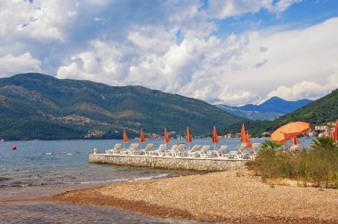 Güneşli yaz gününde plaj şemsiyeli güzel Akdeniz manzarası. Yaz tatili. Karadağ, Kotor Körfezi, Tivat