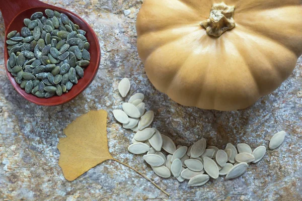 Autumn. Pumpkin and seeds - in shell and peeled. Large wooden spoon with peeled pumpkin seeds