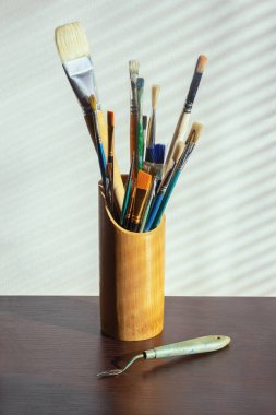 Resim yapmak için farklı türde fırçalar. Arka planda pencere çizgileri olan duvar