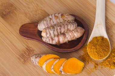 Ahşap arka planda kökler ve zerdeçal tozu (curcuma longa)