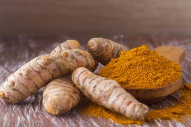 Ahşap arka planda kökler ve zerdeçal tozu (curcuma longa)