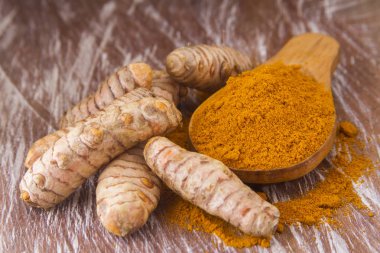 Ahşap arka planda kökler ve zerdeçal tozu (curcuma longa)