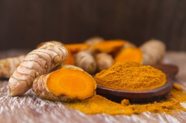 Ahşap arka planda kökler ve zerdeçal tozu (curcuma longa)