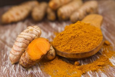 Ahşap arka planda kökler ve zerdeçal tozu (curcuma longa)