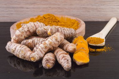 Ahşap arka planda kökler ve zerdeçal tozu (curcuma longa)