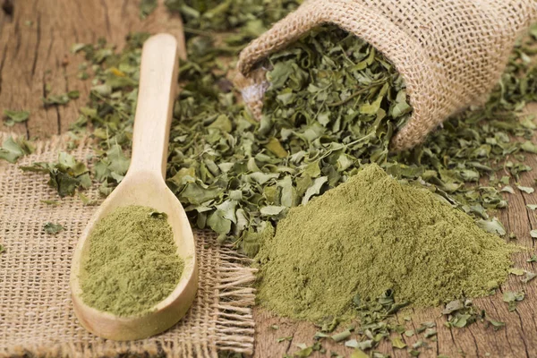 Polvo y hojas de moringa sobre fondo de madera —  Fotos de Stock