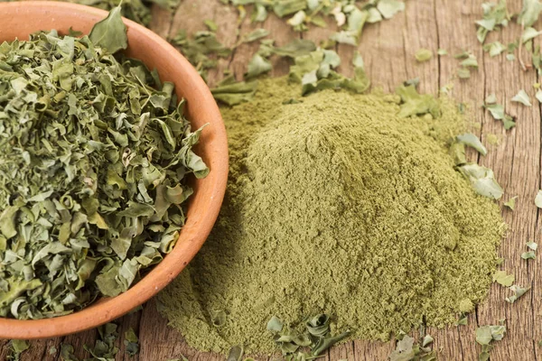 Polvo y hojas de moringa sobre fondo de madera —  Fotos de Stock