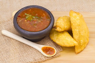 Colombian empanada with spicy sauce on wooden background clipart