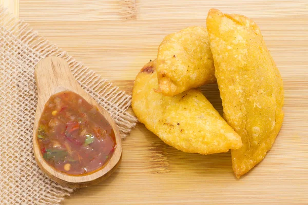 Colombian empanada with spicy sauce on wooden background — Stock Photo, Image