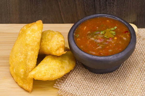 Colombiaanse empanada met pittige saus op houten achtergrond — Stockfoto