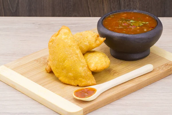 Colombian empanada with spicy sauce on wooden background — Stock Photo, Image