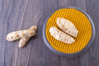 Kökleri ve ahşap arka plan (uzun curcuma üzerinde zerdeçal tozu)