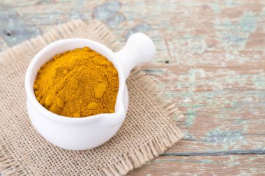 Kökleri ve ahşap arka plan (uzun curcuma üzerinde zerdeçal tozu)