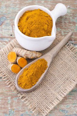 Kökleri ve ahşap arka plan (uzun curcuma üzerinde zerdeçal tozu)