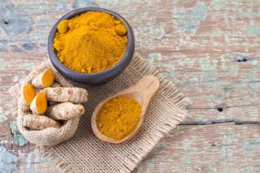 Kökleri ve ahşap arka plan (uzun curcuma üzerinde zerdeçal tozu)
