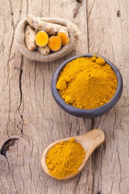 Kökleri ve ahşap arka plan (uzun curcuma üzerinde zerdeçal tozu)