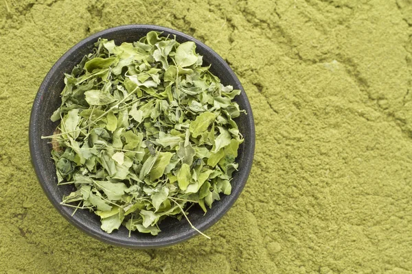 Feuilles et poudre de moringa sur fond bois (moringa olifera — Photo