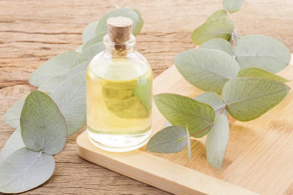 Eucalyptus oil and leaves on wooden table — Stock Photo, Image