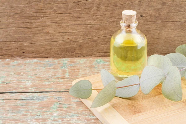 Eucalyptus oil and leaves on wooden table — Stock Photo, Image