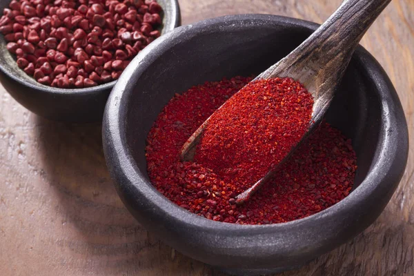 Achiote grains and powder in wooden bowl — Stock Photo, Image