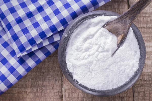 Baking soda in a bowl with spoon and dough cloth on wooden background — Stock Photo, Image