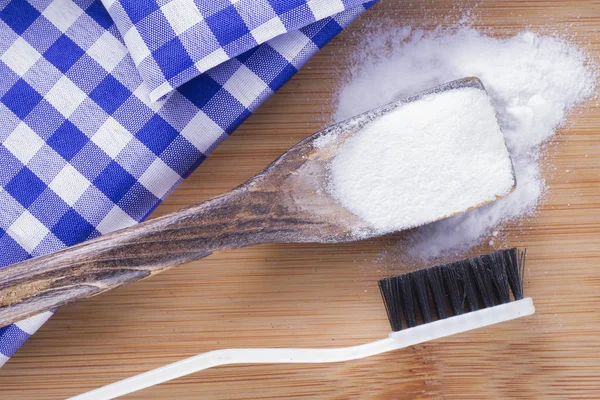 Bicarbonato de sódio e escova na mesa de madeira — Fotografia de Stock