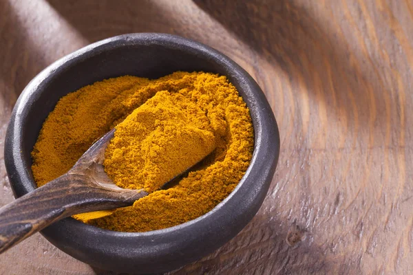 Kase ve ahşap masa (curcuma longa kaşık zerdeçal tozu)