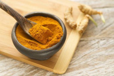 Kase ve ahşap masa (curcuma longa kaşık zerdeçal tozu)
