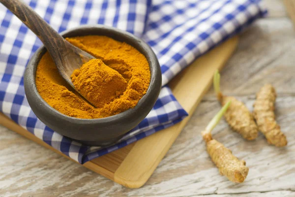 Polvo de cúrcuma en tazón y cuchara sobre mesa de madera (curcuma longa ) — Foto de Stock