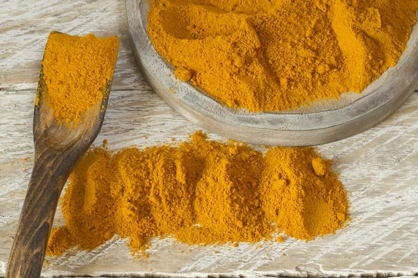 Kase ve ahşap masa (curcuma longa kaşık zerdeçal tozu)