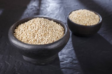 Quinoa Tahıl kaşık ve siyah arka plan üzerine kase
