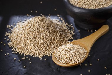 Quinoa Tahıl kaşık ve siyah arka plan üzerine kase