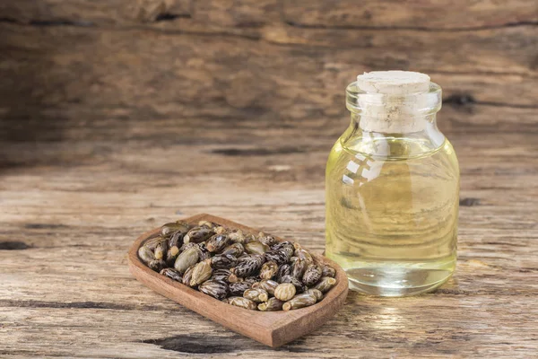 Grains and castor oil on old wood — Stock Photo, Image