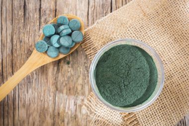Spirulina toz ve tabletler ahşap arka plan üzerinde