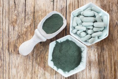 Spirulina toz ve tabletler ahşap arka plan üzerinde
