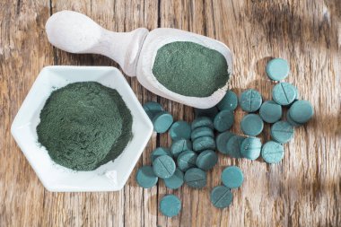 Spirulina toz ve tabletler ahşap arka plan üzerinde