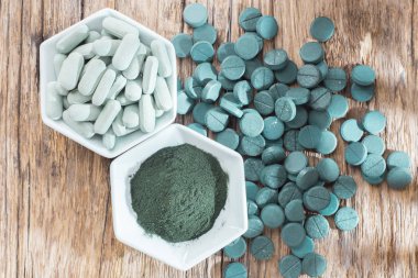 Spirulina toz ve tabletler ahşap arka plan üzerinde