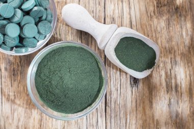 Spirulina toz ve tabletler ahşap arka plan üzerinde