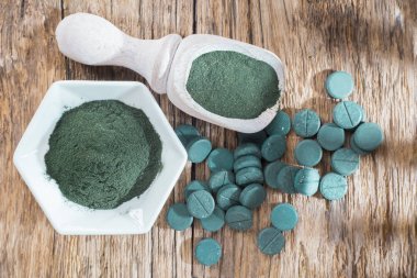 Spirulina toz ve tabletler ahşap arka plan üzerinde