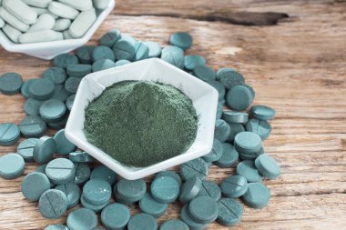 Spirulina toz ve tabletler ahşap arka plan üzerinde