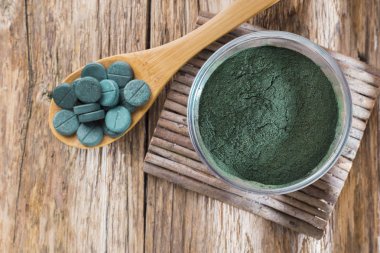 Spirulina toz ve tabletler ahşap arka plan üzerinde