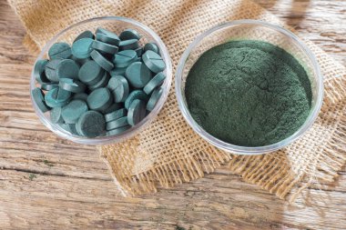 Spirulina toz ve tabletler ahşap arka plan üzerinde